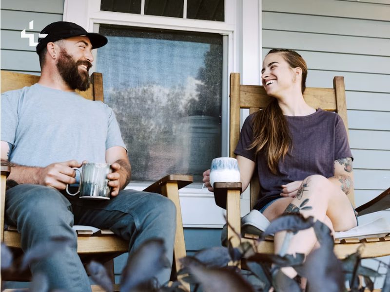 Two neighbors sharing a laugh and a conversation on a front porch