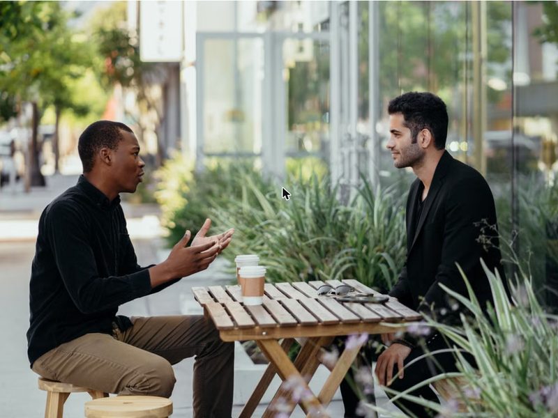 Two colleagues talking to each other at an outdoor café table